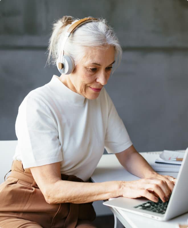 Older woman with headphones looking at her computer